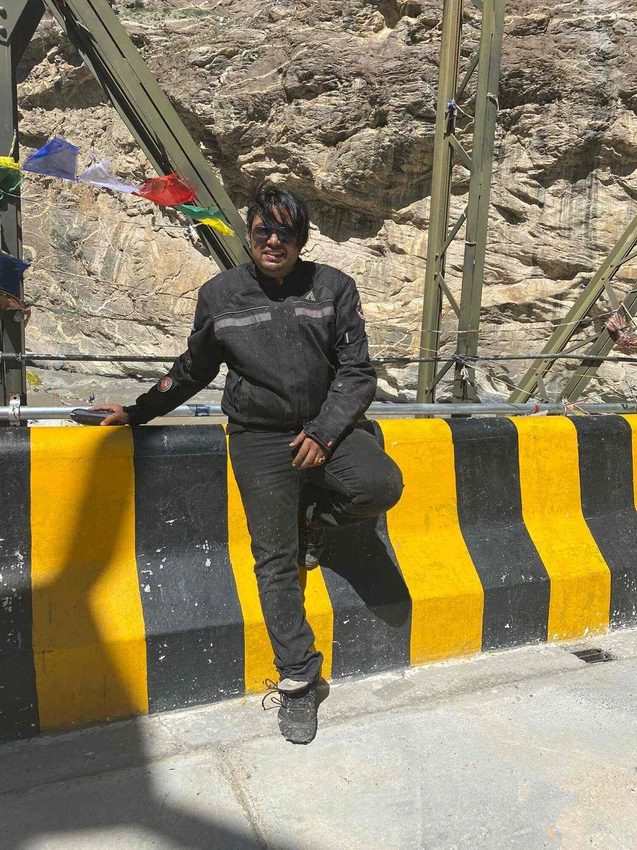 The owner in a rain jacket on a road barrier, a steel bridge and rock behind