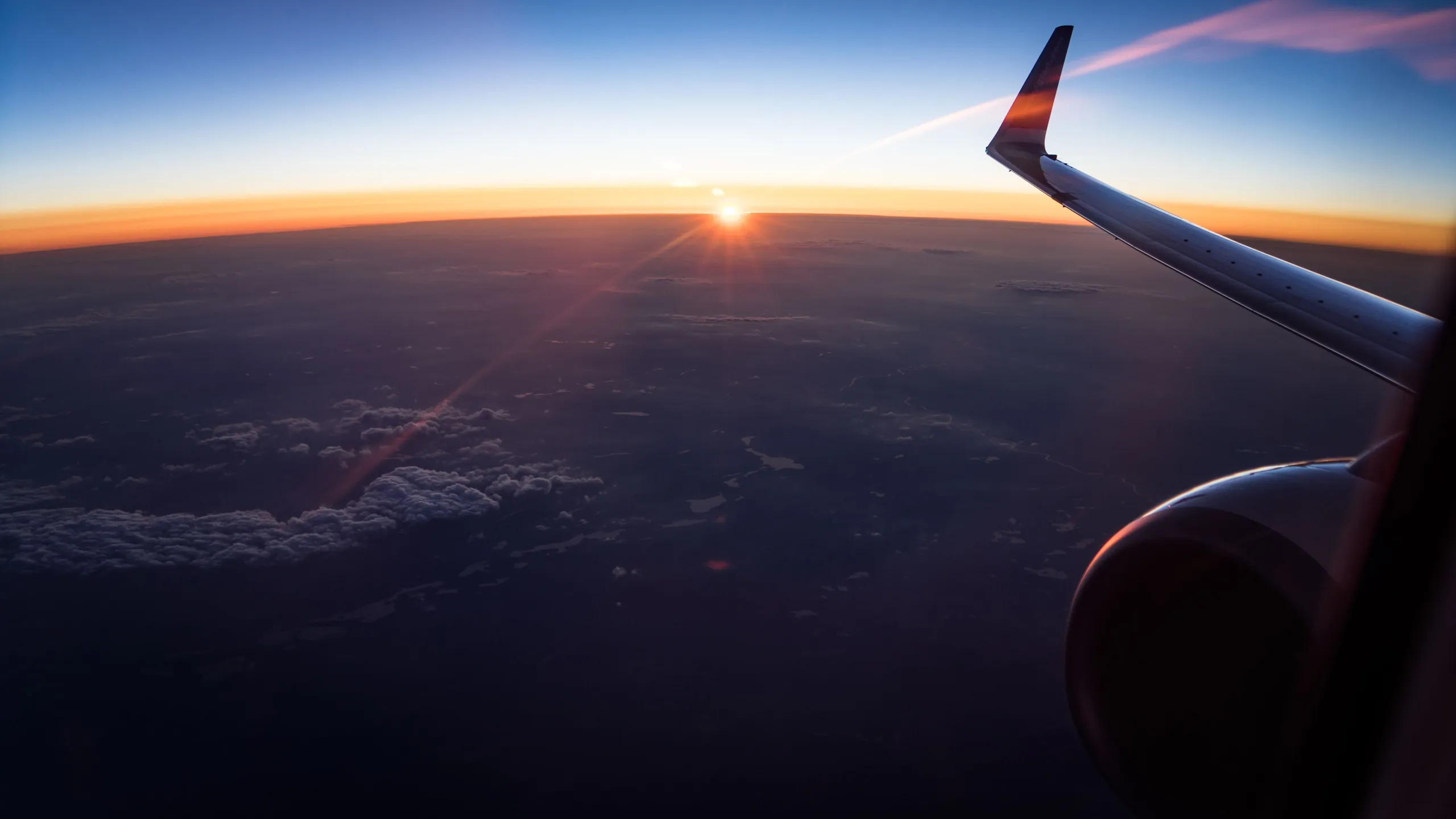 The curve of the earth at sunrise beyond an aircraft wing