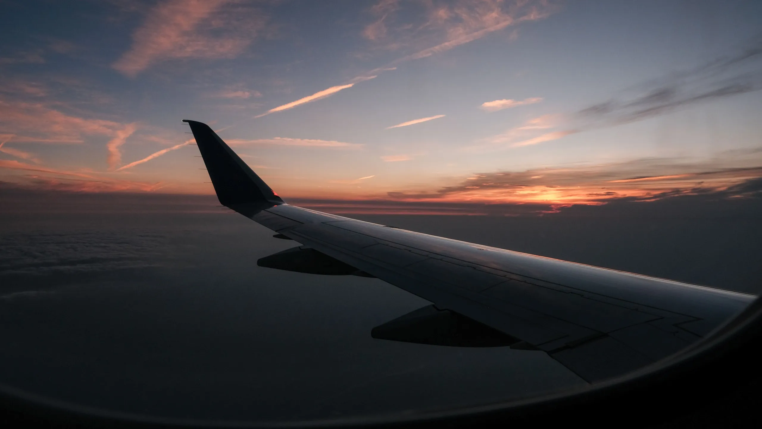 An aircraft wing above the clouds at sunset