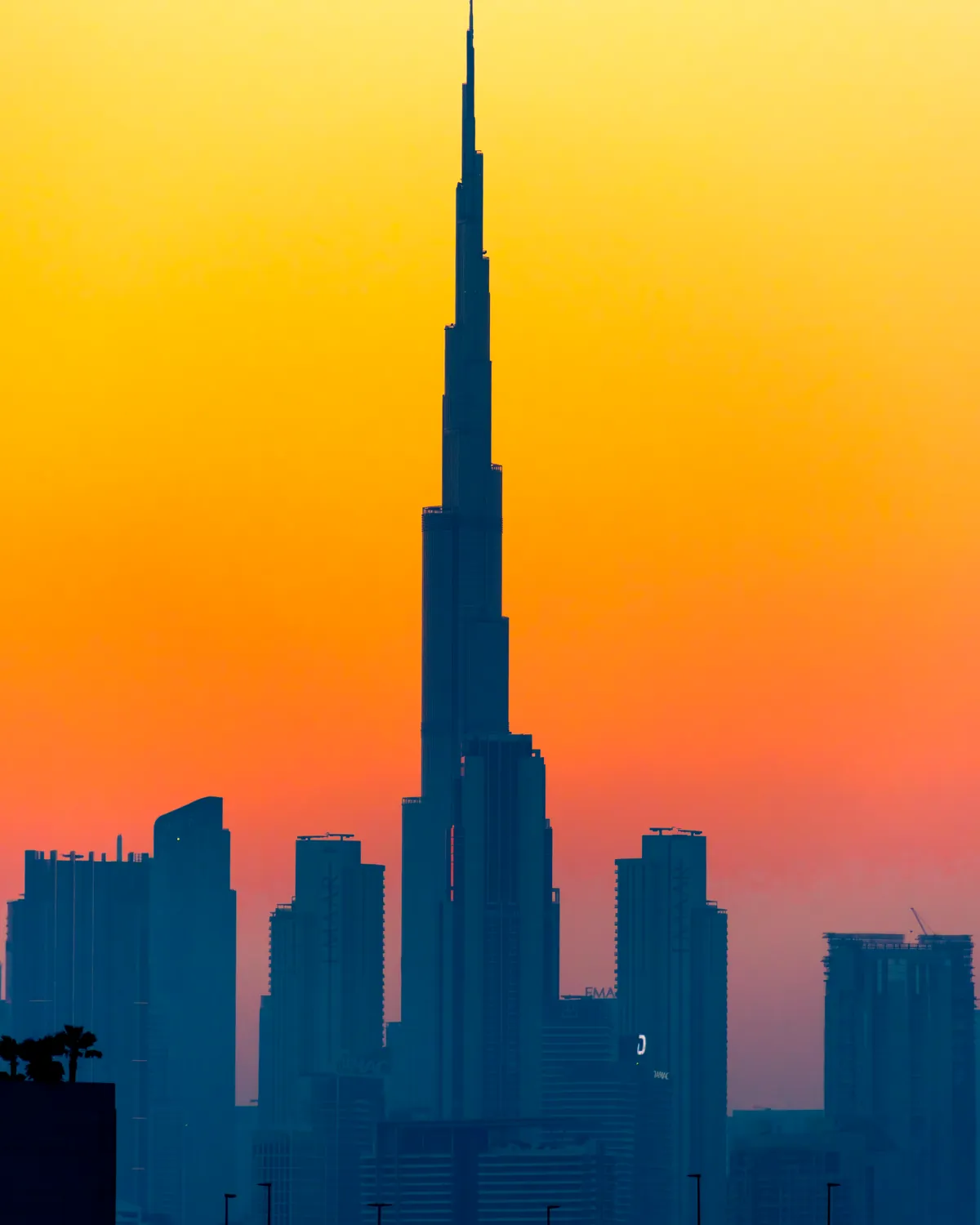 The Burj Khalifa in silhouette against an orange sunset sky, Dubai