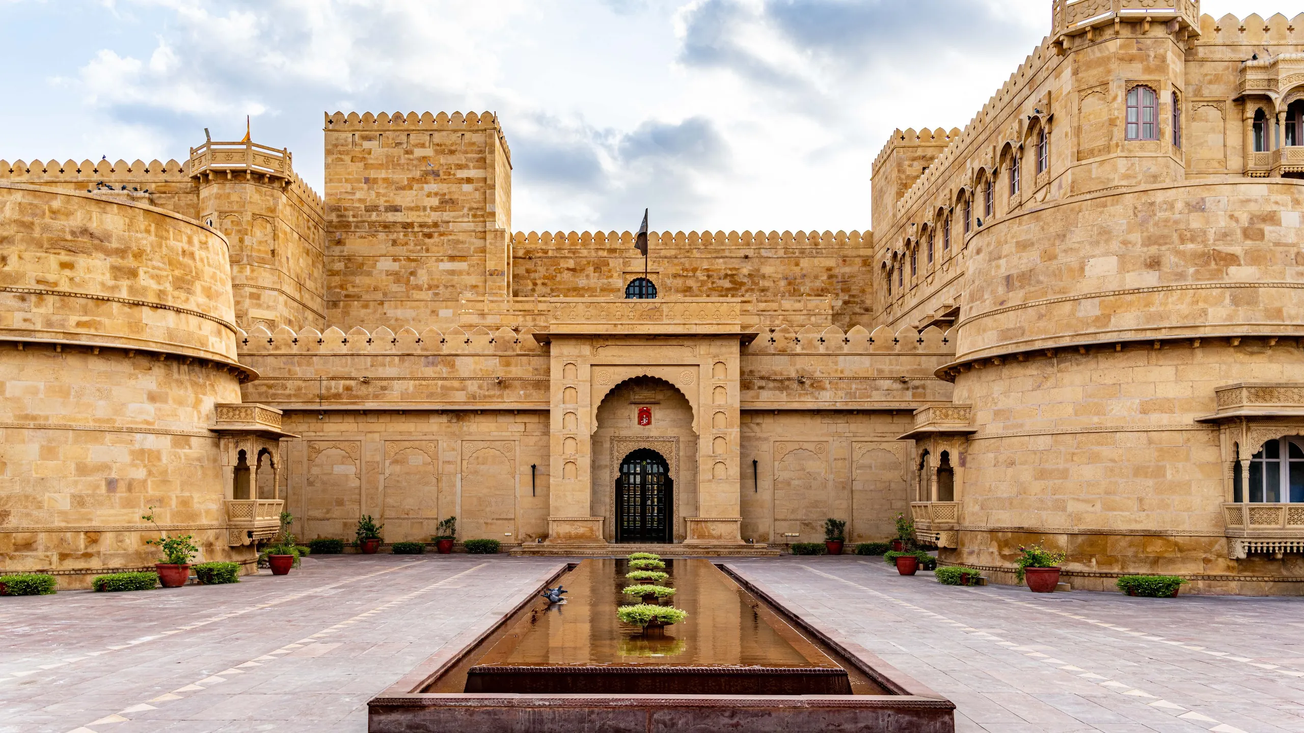 A sandstone palace courtyard with a long pool in Rajasthan