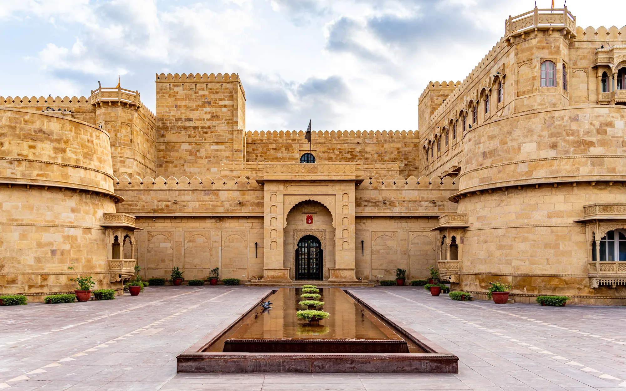 A sandstone palace courtyard with a long pool in Rajasthan