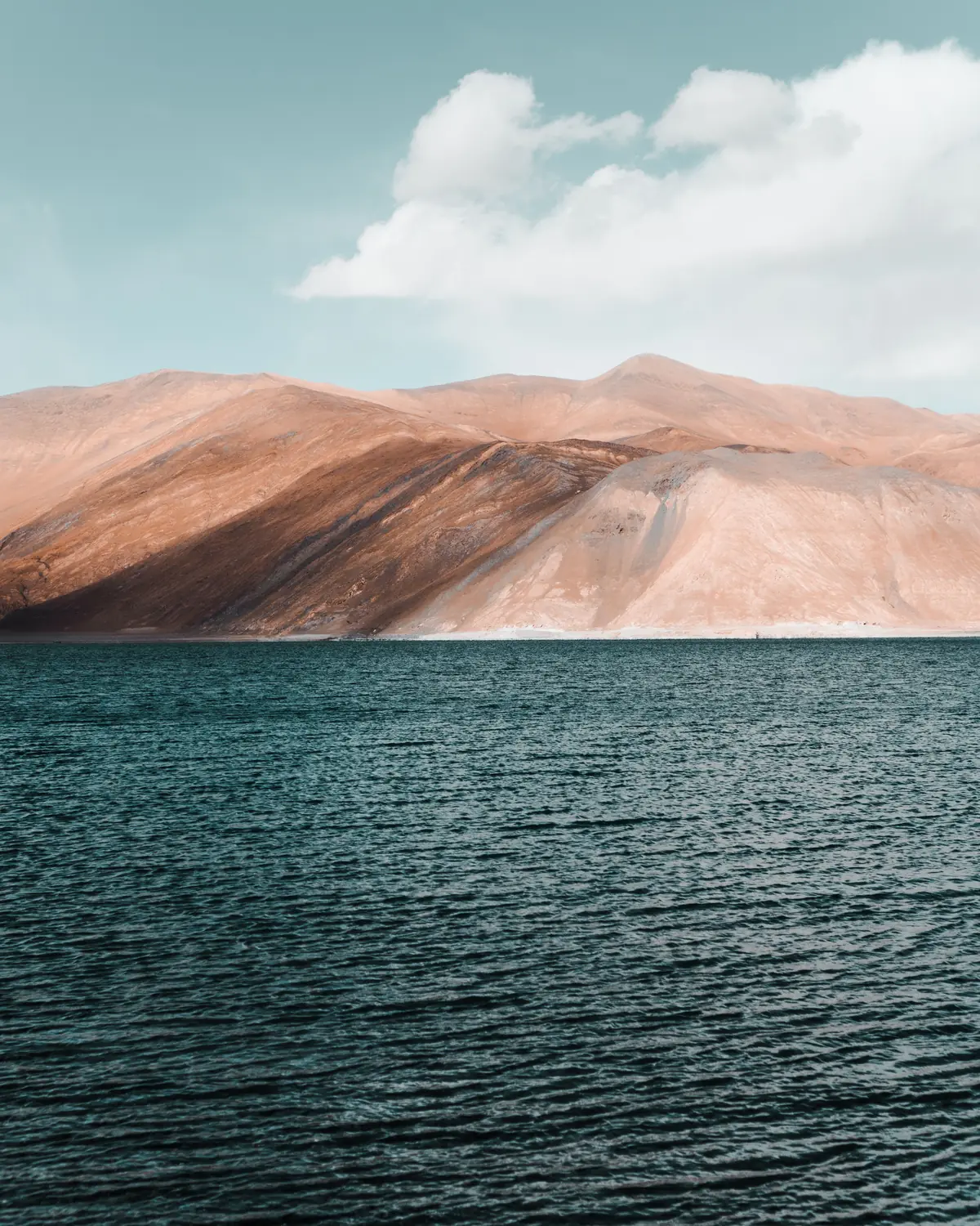 Bare brown mountains above the dark blue water of Pangong lake, Ladakh