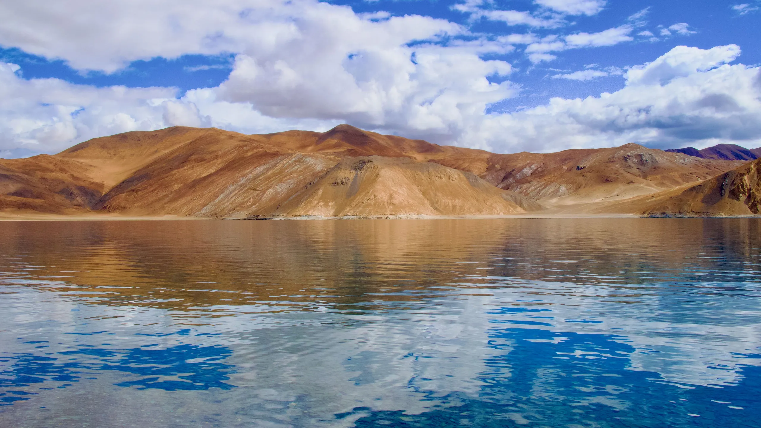 Clouds and brown hills reflected in the still water of Pangong lake, Ladakh